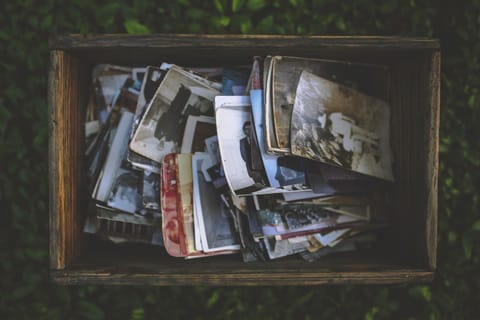 An old wooden crate crammed with curling black-and-white and sepia family photographs.